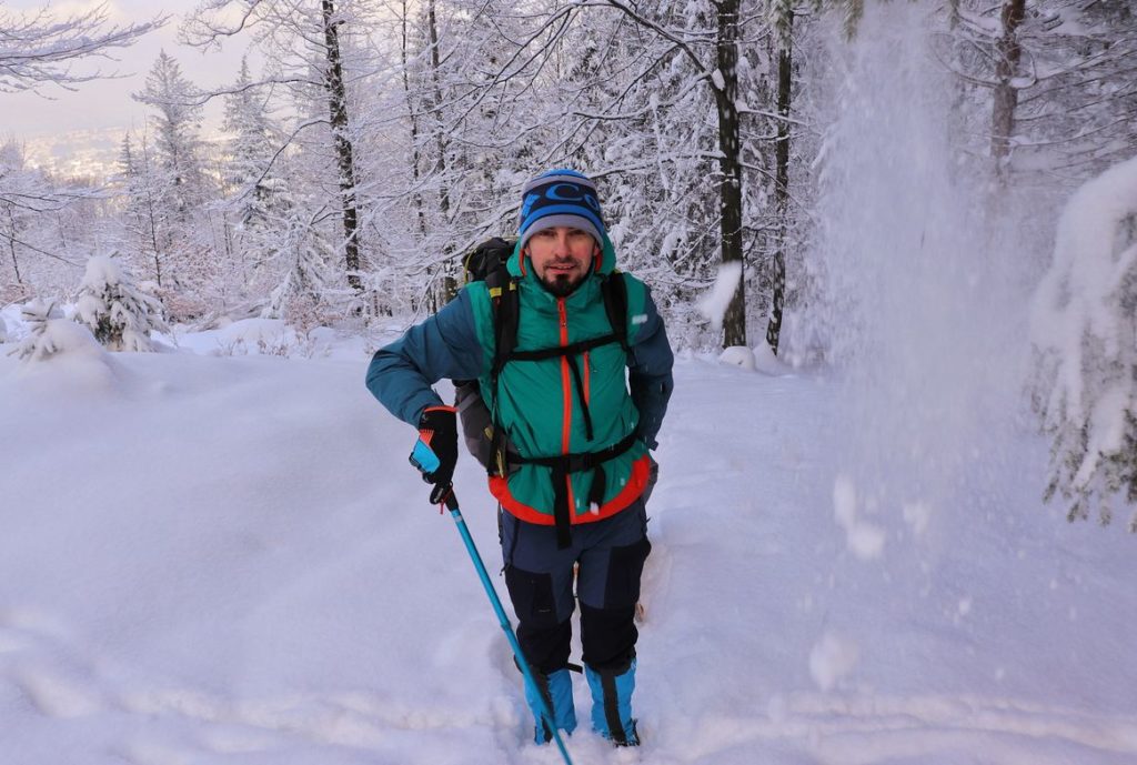 Zadowolony turysta, zaśnieżona, leśna ścieżka