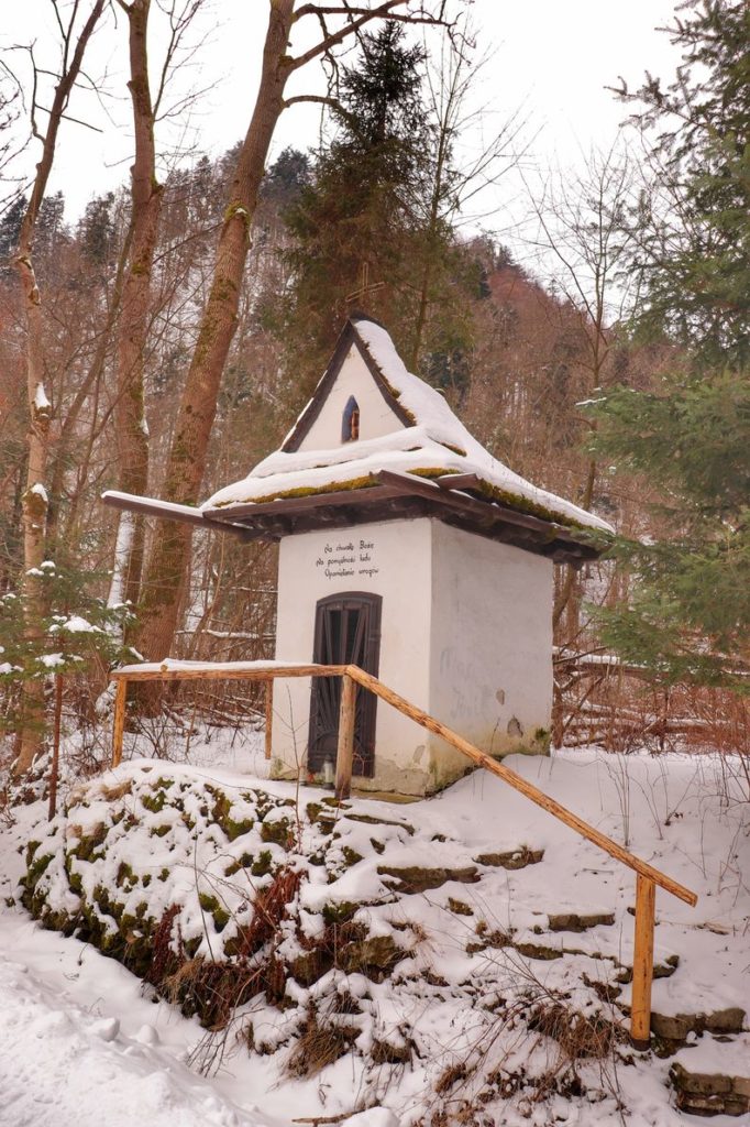Biała kapliczka leśna stojąca przy zielonym szlaku na Sokolicę w Krościenku, zimowa sceneria