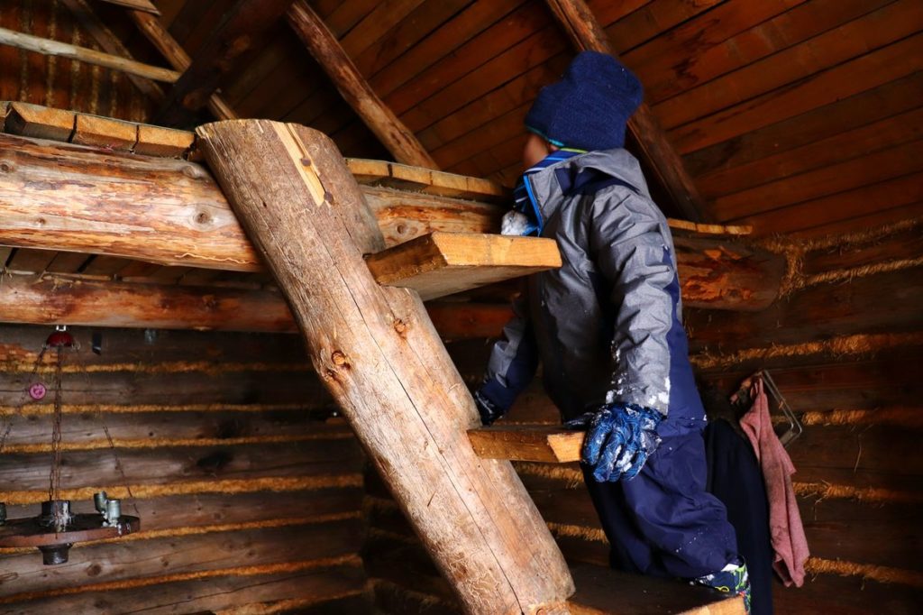 Dziecko stojące na drewnianej drabinie w chacie na Suchej Górze