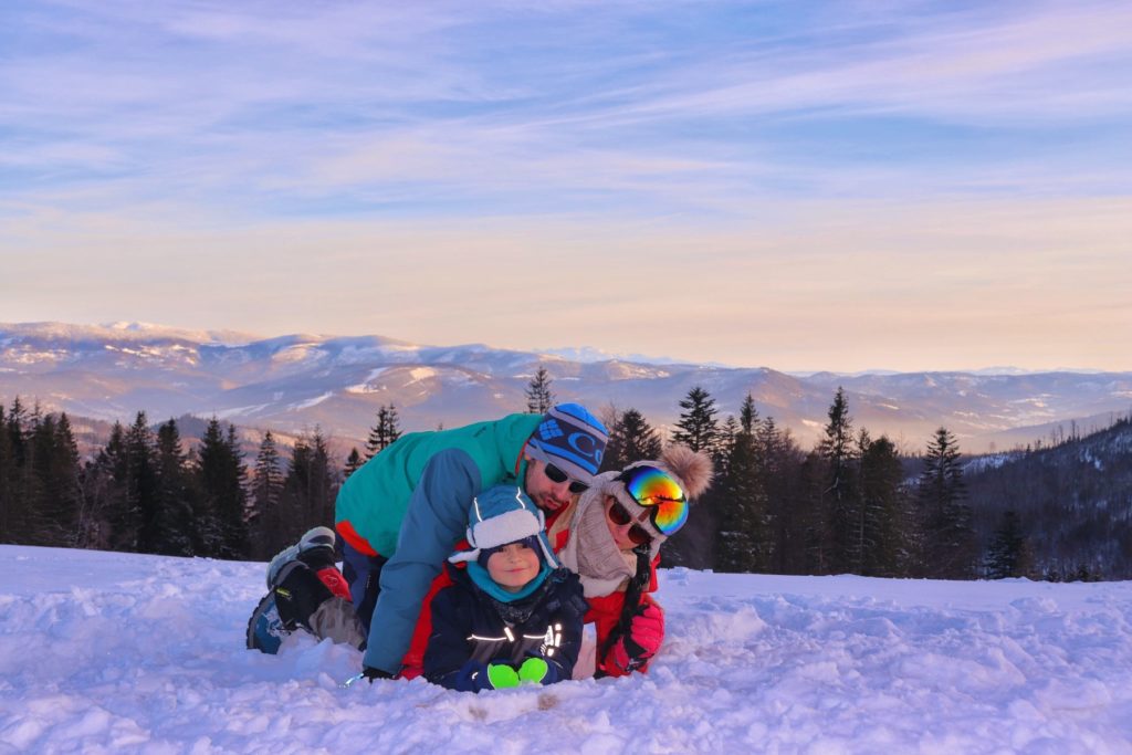 Szczęśliwa rodzina leżąca w śniegu na Hali Baraniej, w tle piękny krajobraz górski