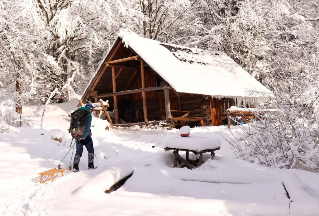 Turysta idący do drewnianej chaty Sucha Góra, zimowa sceneria