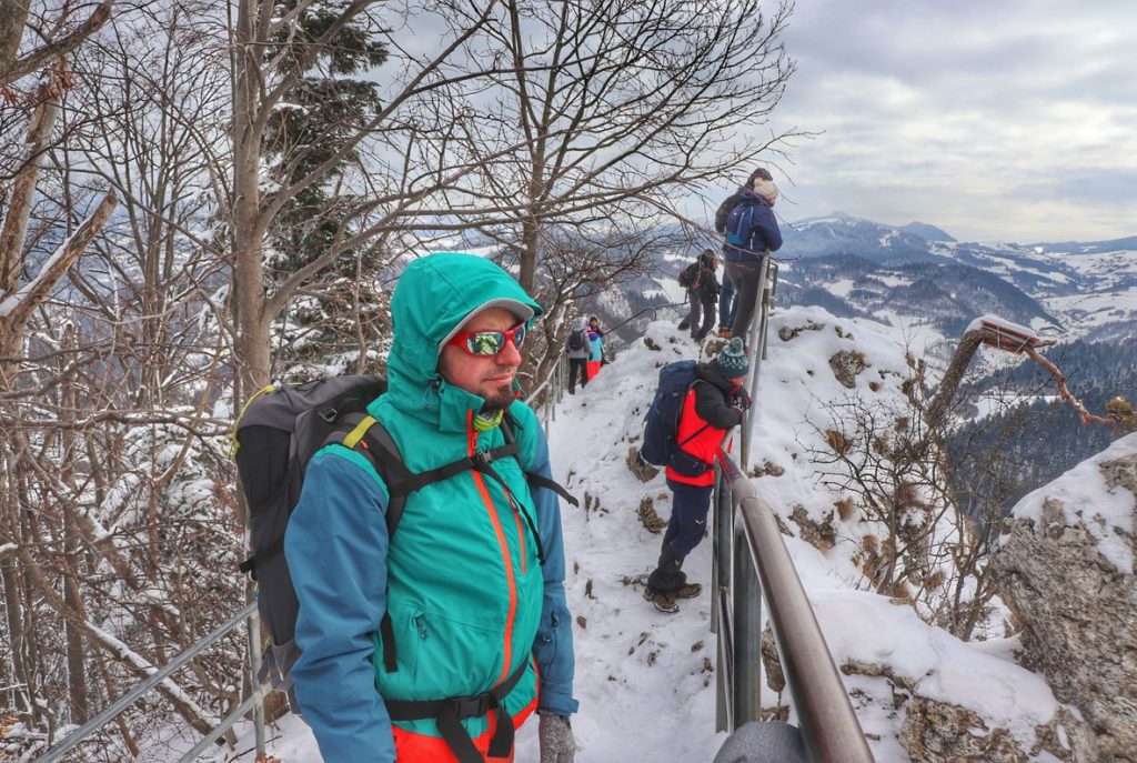 Turysta podziwiający zimowe widoki z pienińskiej Sokolicy, w tle inni turyści będący na punkcie widokowym na Sokolicy