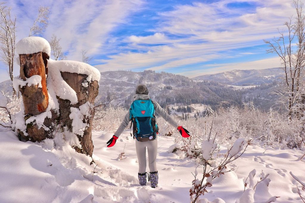 Turystka podziwiająca zimowy krajobraz Górski - Beskidy, niebieskie niebo z białymi chmurami, bajkowa zima