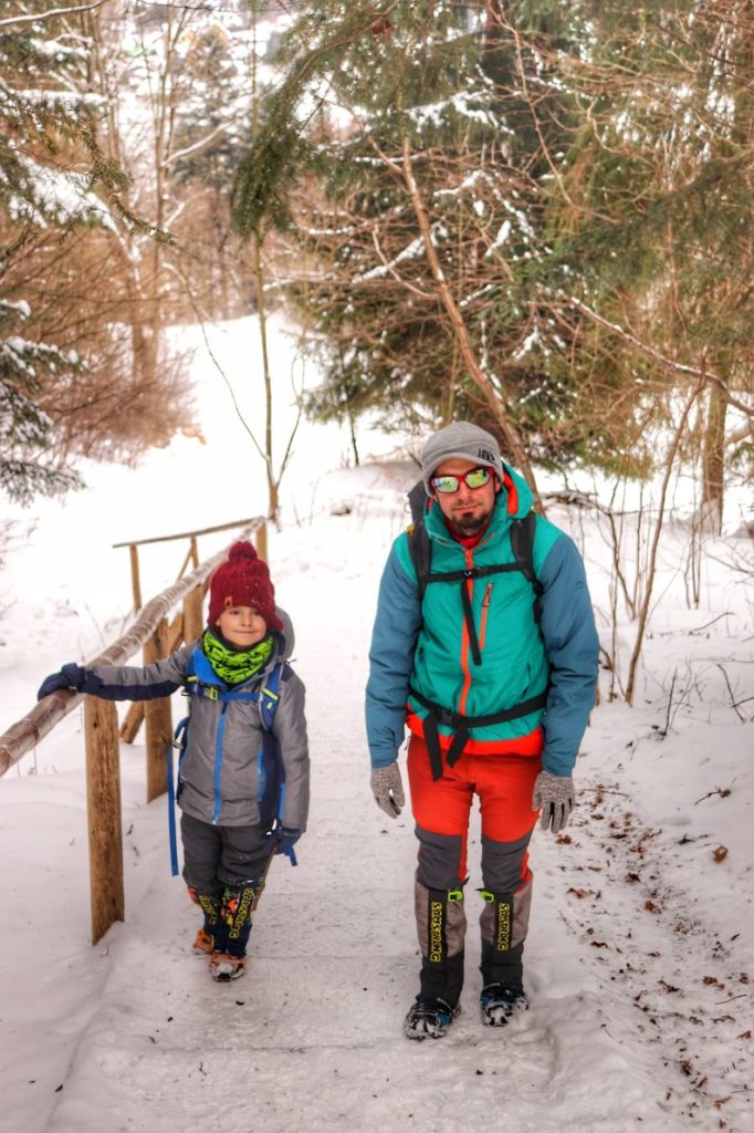 Turyści - dziecko oraz mężczyzna, zaśnieżone drewniane schody na szlaku zielonym na Sokolicę, las
