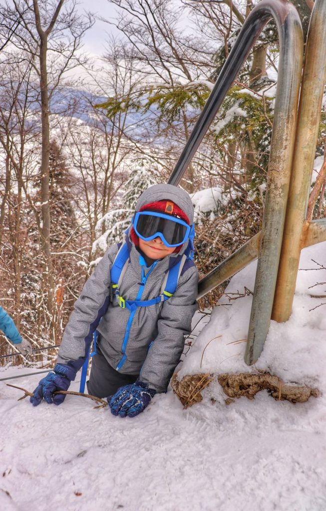 Uśmiechnięte dziecko na ostatnim podejściu na szczyt Sokolica w Pieninach, śnieg, barierki