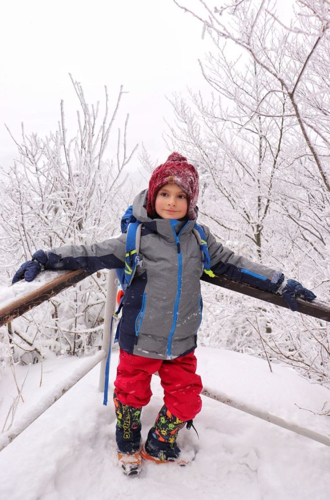Uśmiechnięte dziecko na tarasie widokowym na niebieskim szlaku na Wysoką, zima