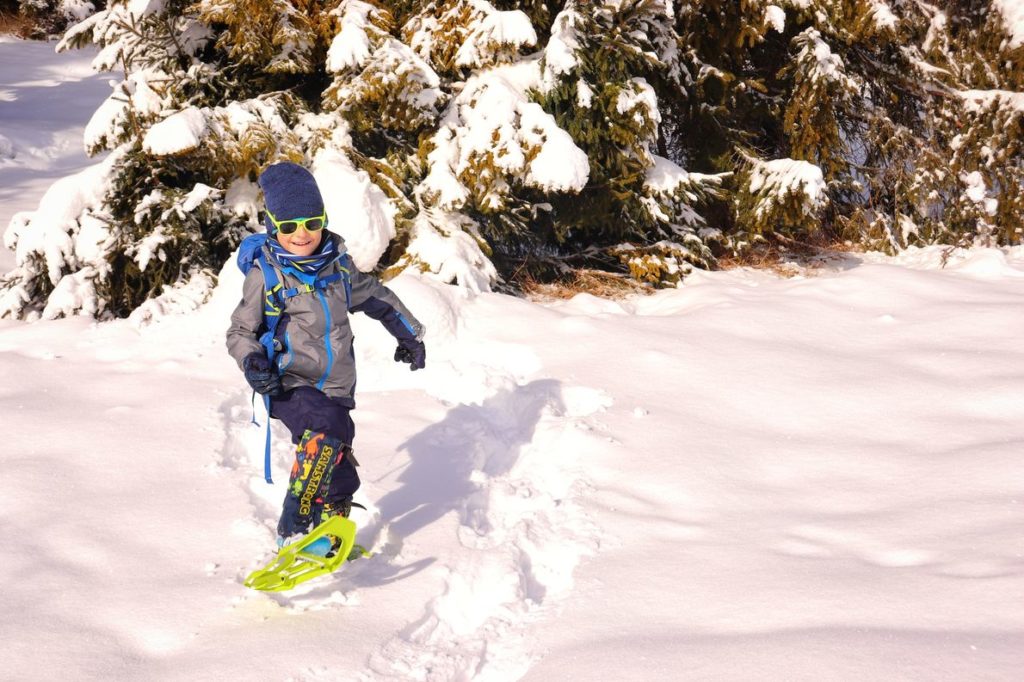Uśmiechnięte dziecko z założonymi rakietami śnieżnymi, duże ilości śniegu w lesie w Rajczy