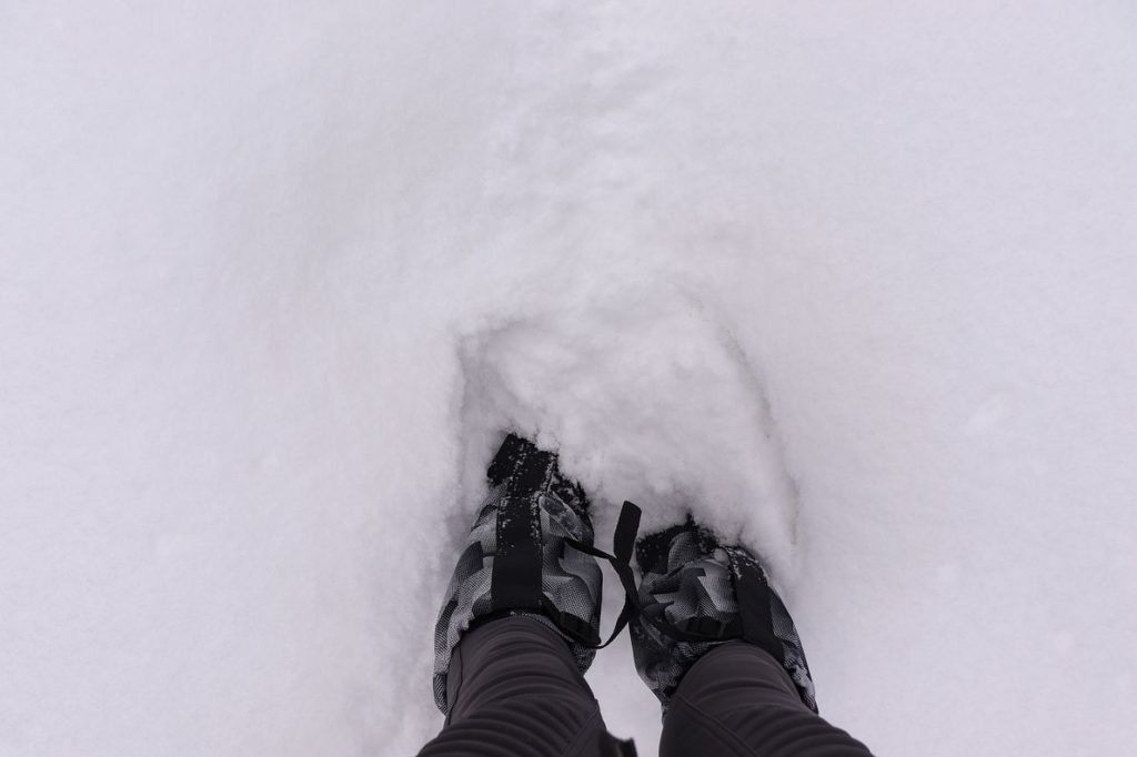 Zaśnieżona droga, buty zakopane w śniegu