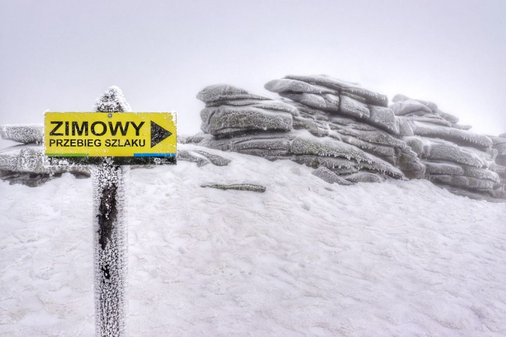 Bloki skalne na Śnieżnych Kotłach, mróz, żółta tabliczka z napisem - ZIMOWY PRZEBIEG SZLAKU na Śnieżne Kotły