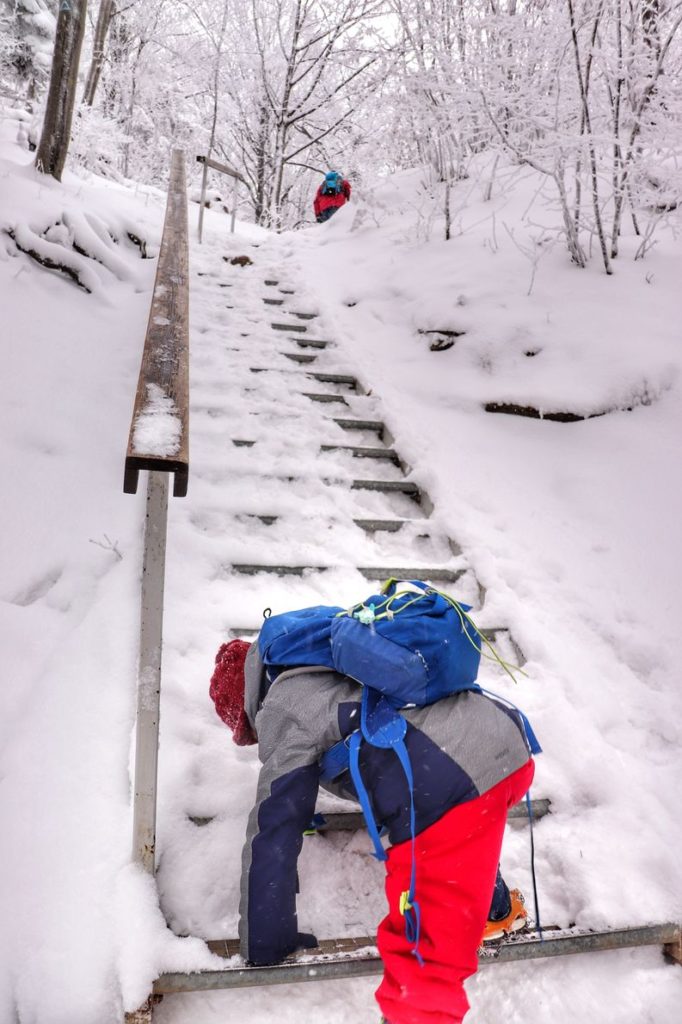 Dziecko wychodzące na metalowe, pokryte śniegiem schody na niebieskim szlaku idącym na Wysoką w Pieninach