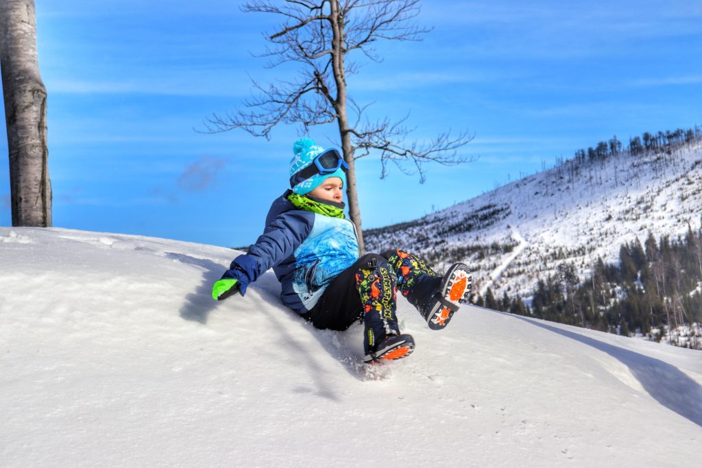Dziecko zjeżdżające z górki, snieg, błękitne niebo, okolice szcytu Malinów w Beskidzie Śląskim