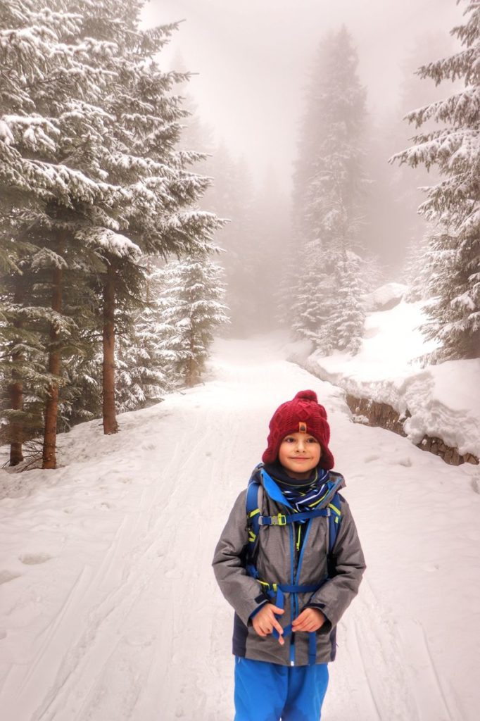 Mały turysta - dziecko, szeroka, pokryta śniegiem droga, mgła