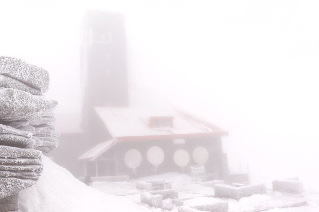 Mgła na Śnieżnych Kotłach, ledwo widoczny budynek, w którym działa Radiowo Telewizyjny Ośrodek Nadawczy Jelenia Góra - Śnieżne Kotły, skały, zima