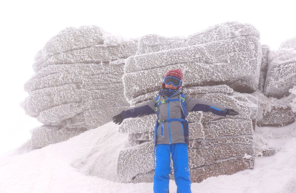 Szczęśliwe dziecko na tle skał znajdujących się na Śnieżnych Kotłach, zima