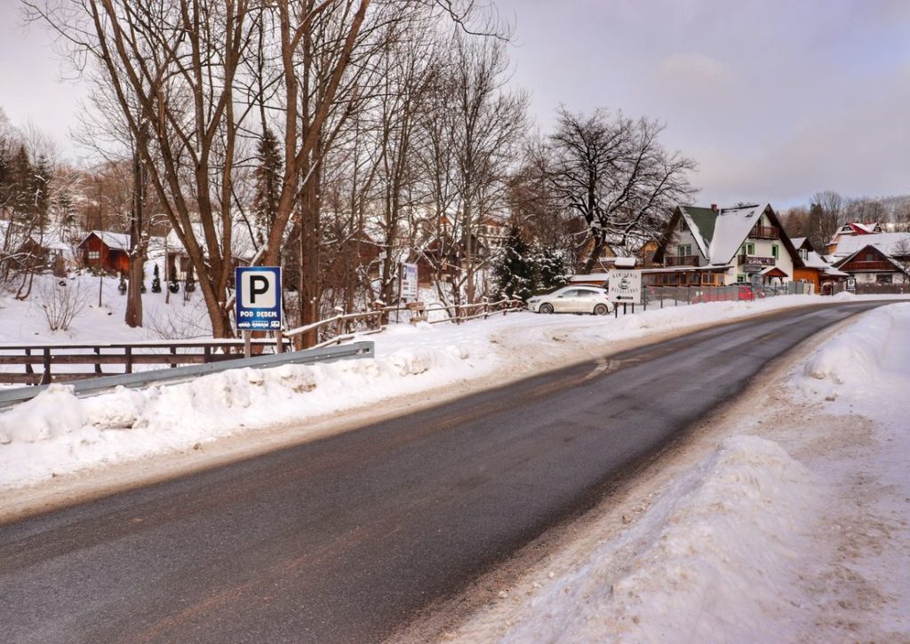 Szeroka droga asfaltowa w Jaworkach, dojazd do parkingu pod Dębem przy szlaku zielonym idącym na szczyt Wysoka, zima