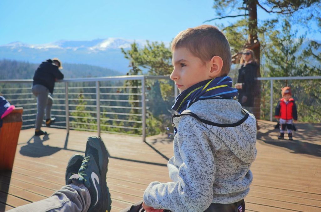 Turyści, dziecko odpoczywające na leżaku na platformie widokowej Złoty Widok, w oddali karkonoskie szczyty
