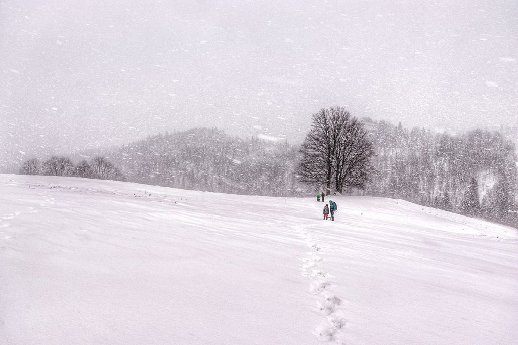 Turysta z dzieckiem idący w górę Polany pod Wysoką, zima, padający śnieg
