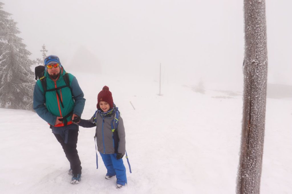 Turysta z uśmiechniętym dzieckiem na zimowym przebiegu szlaku na Śnieżne Kotły, mgła, siarczysty mróz