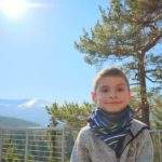 Uśmiechnięte dziecko na platformie widokowej Złoty Widok w Górach Izerskich, w tle zaśnieżone Śnieżne Kotły