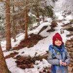 Uśmiechnięte dziecko na żółtym szlaku w Karkonoskim Parku Narodowym, leśna, kamienista ścieżka, pokryta śniegiem