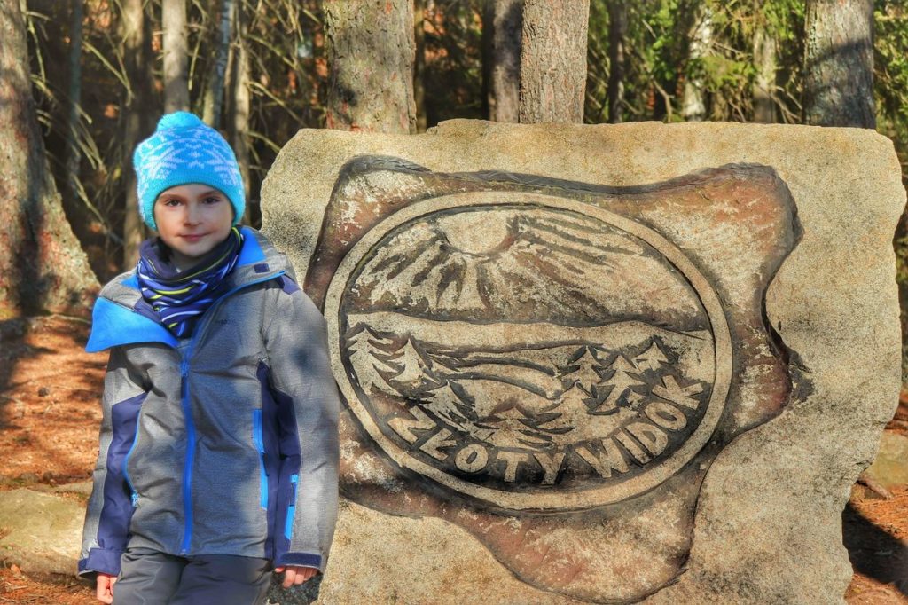 dziecko (uśmiechnięte) przy skale z napisem Złoty Widok, las