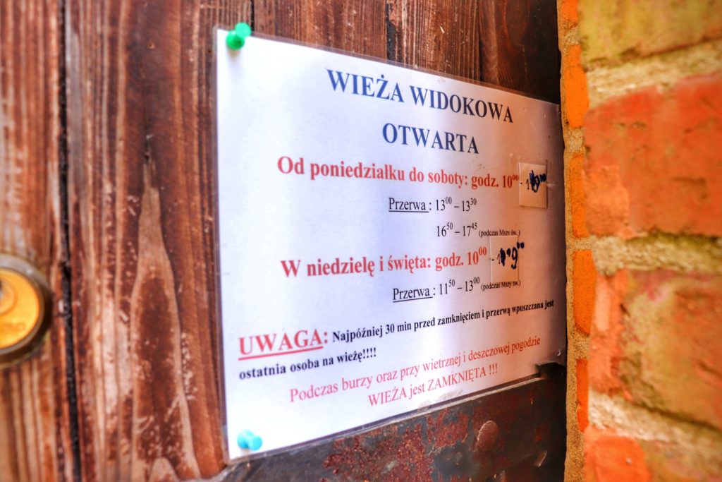 Biała kartka, na której wypisane są godziny otwarcia, przerwy na wieży widokowej na Górze Chełmskiej w Koszalinie