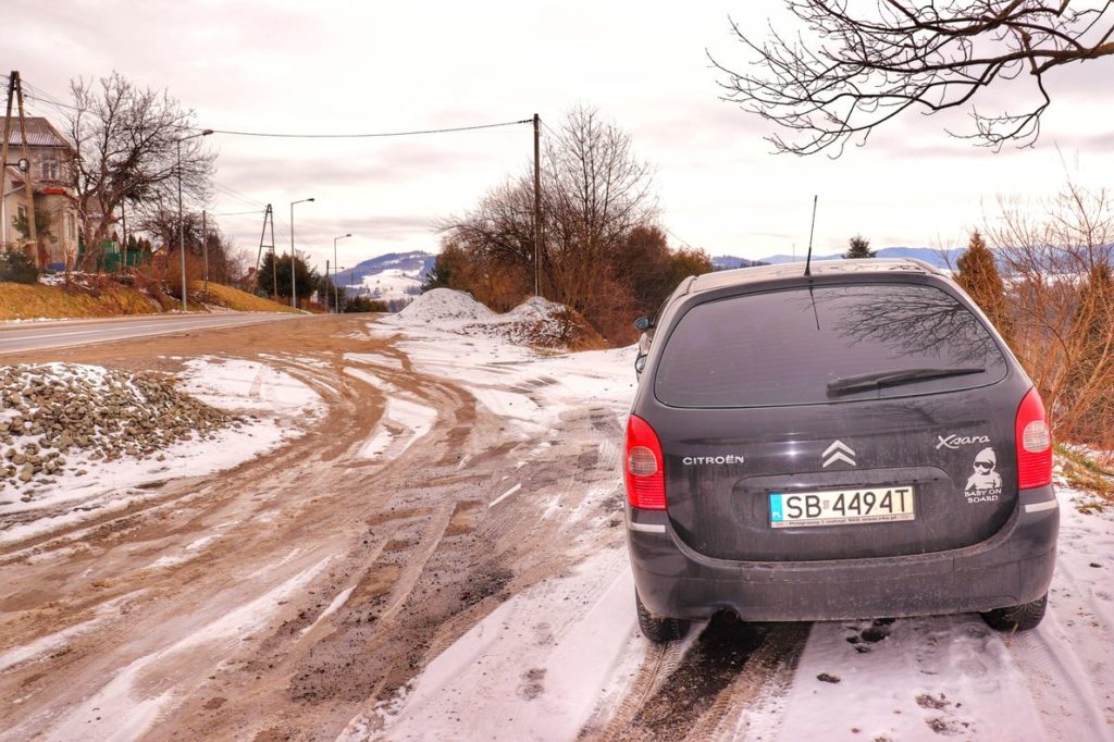 Czarny samochód zaparkowany na zatoczce przy głównej drodze w Rabce Zaryte, zimowy poranek