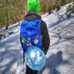 Dziecko idące wąską ścieżką leśną, chłopiec ma przywiązany do plecaka balon z liczbą 7