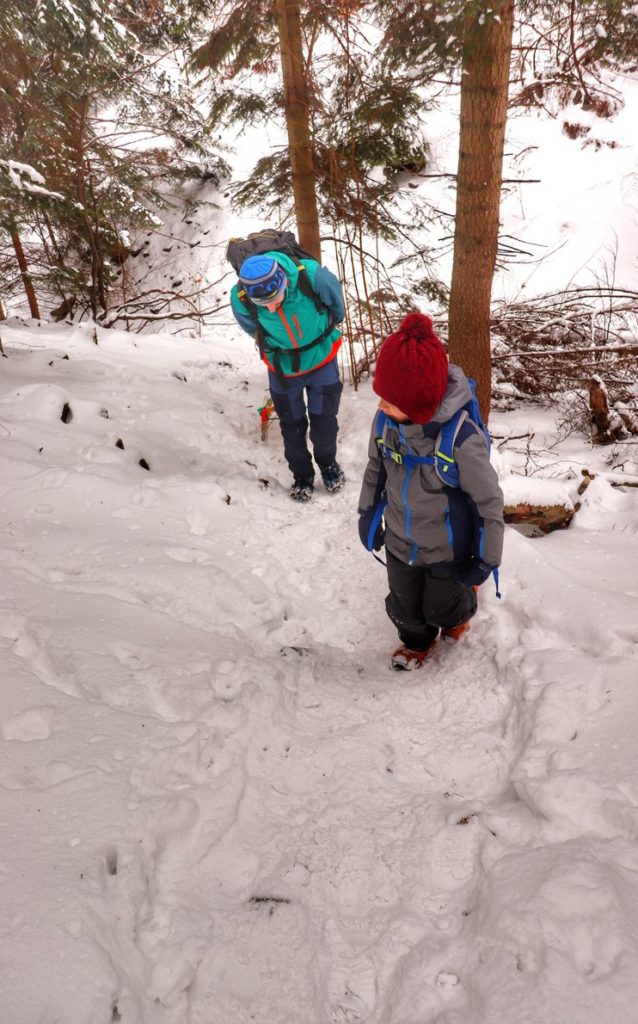 Dziecko z tatą pokonujący podejście idące w stronę Perci Borkowskiego, śnieg