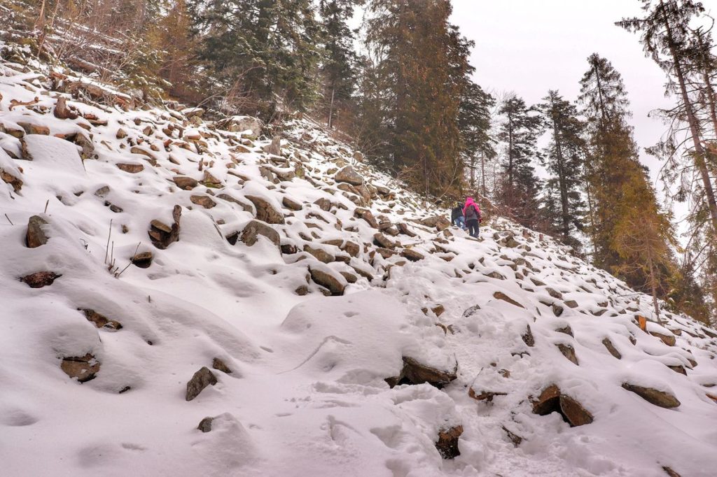 Perć Borkowskiego zimą, duże ilości zalegającego na głazach śniegu, w oddali widoczni turyści