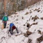 Perć Borkowskiego z dzieckiem zimą (szlak żółty), dziecko wspinające się po głazach, za którym idzie turysta