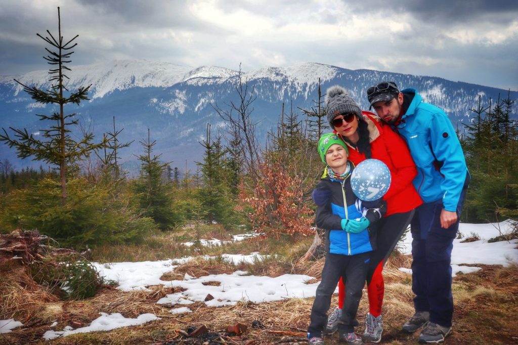 Szczęśliwa rodzina pozująca na tle Babiej Góry na czarnym szlaku idącym z Zawoi, pochmurny, wiosenny dzień