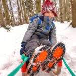 Szczęśliwe dziecko siedzące na drewnianych sankach, leśna droga - Beskid Wyspowy