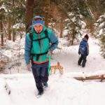 Turysta ciągnący drewniane sanki pod górkę na żółtym szlaku na Luboń Wielki, droga leśna