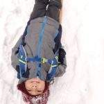 Uśmiechnięte dziecko leżące na plecach na drewnianych sankach