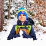 Uśmiechnięte dziecko odpoczywające przy drewnianym stole z ławkami na szlaku żółtym - Rabka Zaryte