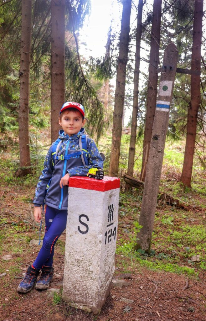 Dziecko na szczycie Krawców Wierch, chłopiec opiera się o słupek graniczny (szlak niebieski)