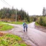 Mężczyzna z dzieckiem, droga asfaltowa, oznaczenie na słupie - szlak żółty oraz szlak niebieski w Soblówce odbija w prawo