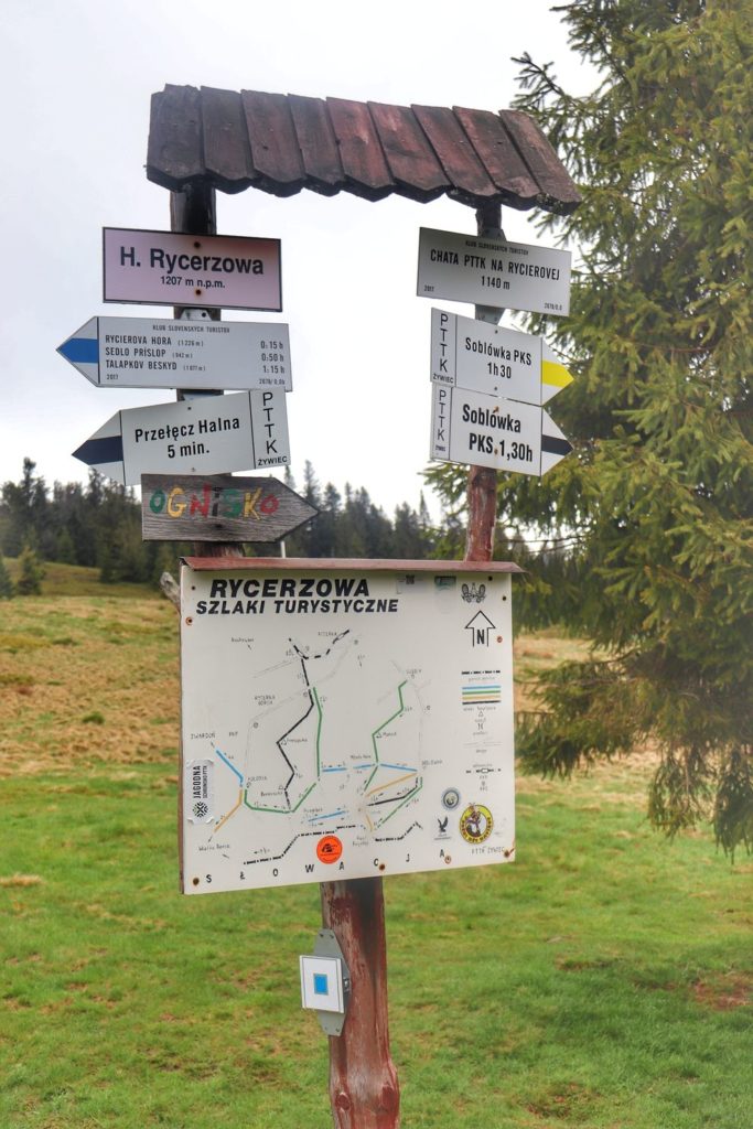 Opis szlaków prowadzących z okolic schroniska na Rycerzowej, biała tabliczka z napisem Hala Rycerzowa 1207 m n.p.m. + mapa