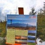 Tablica informacyjna - Babiogórskie ścieżki Poznaj Babią Górę ustawiona przy drewnianej wiacie - punkt widokowy na czarnym szlaku z Zawoi