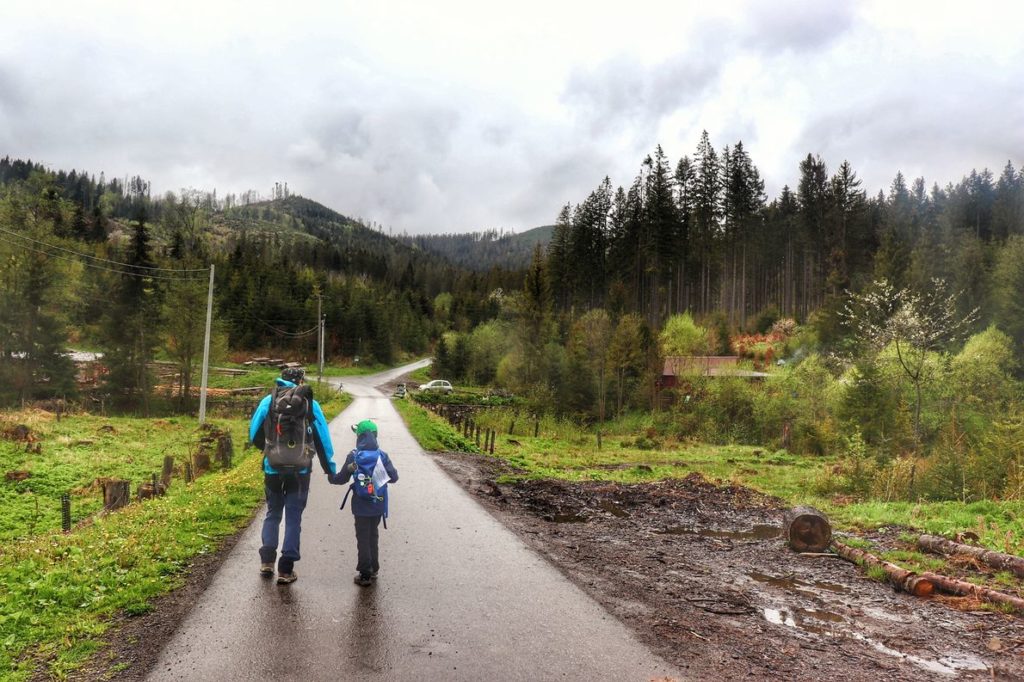 Turysta z dzieckiem, droga asfaltowa na żółtym szlaku w Soblówce, pochmurny dzień