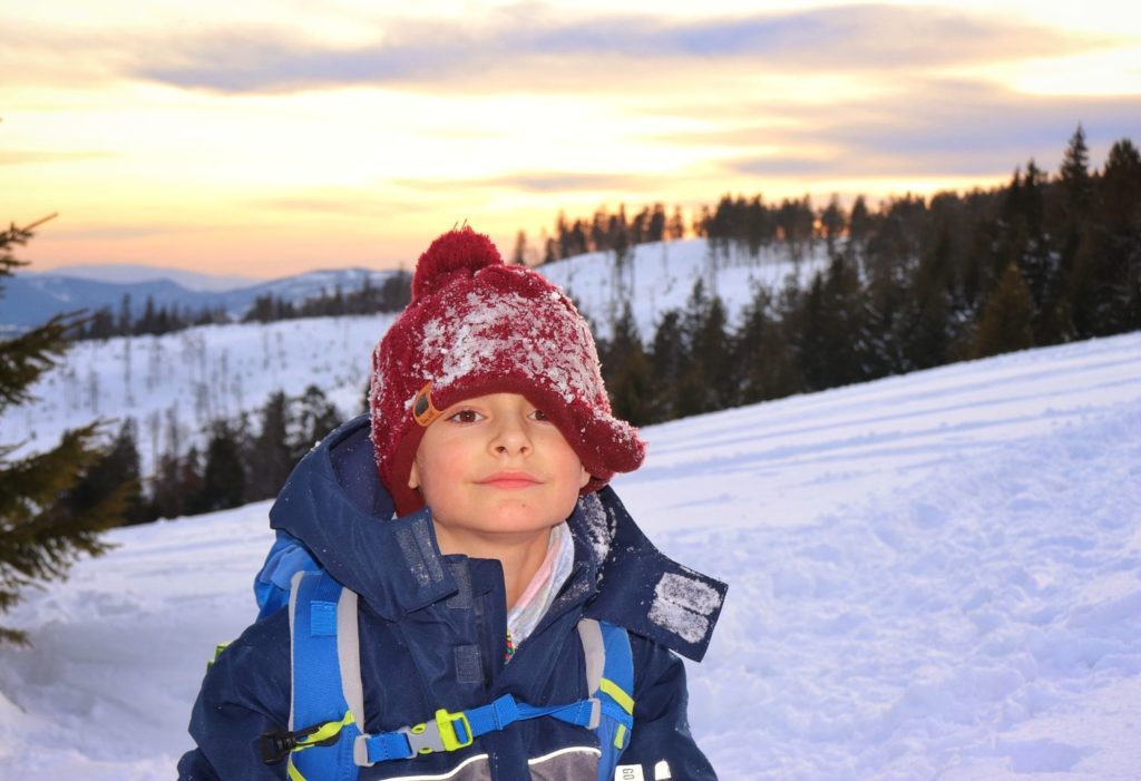 Zadowolone dziecko, niebo zakolorowane przez zachodzące słońce, zimowa Rysianka
