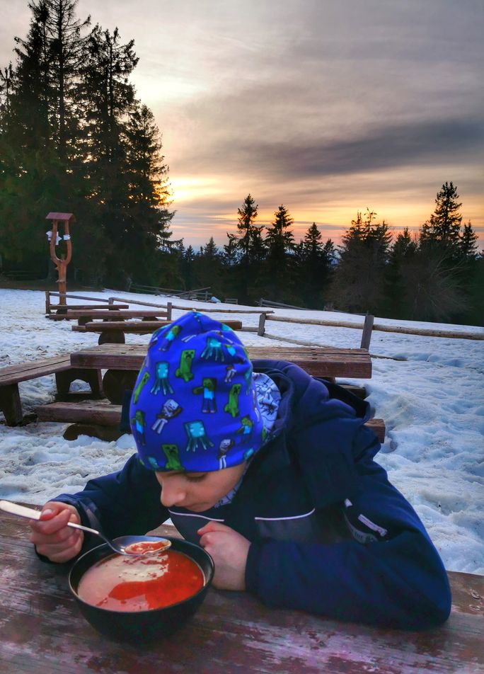 Dziecko jedzące zupę przy schronisku - Krawców Wierch, w tle zachód słońca