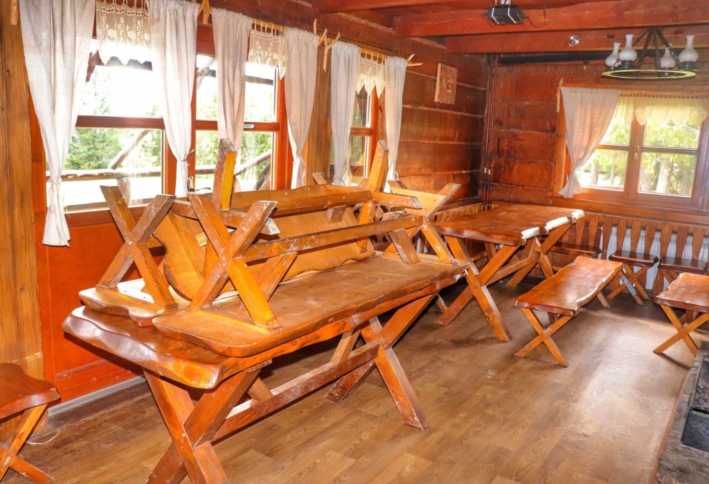 Wnętrze schroniska na Krawcowym Wierchu, drewniane stoły, ławki
