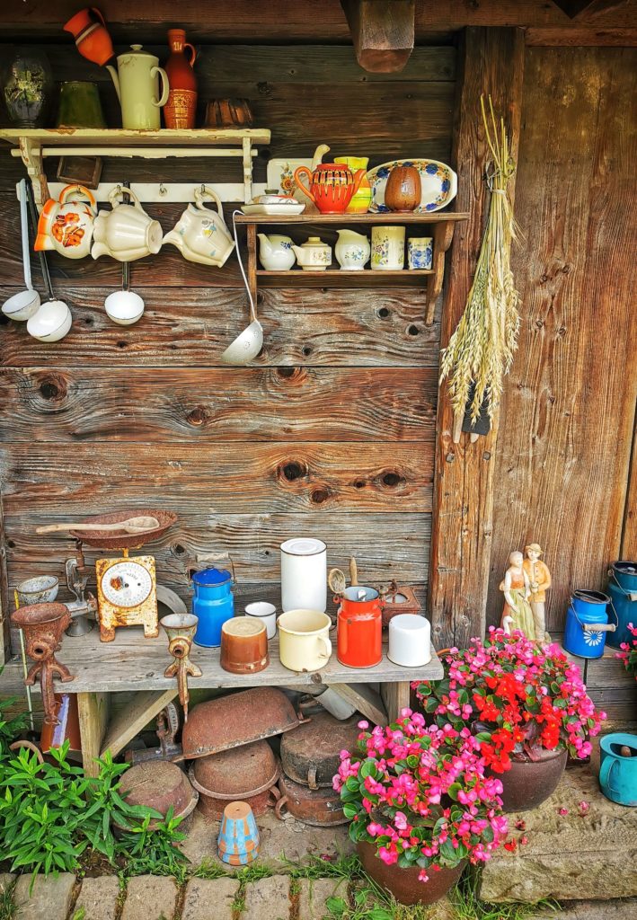 Gliniane naczynia, drewniane łyżki, misy, kwiaty, drewniana chata wiejska