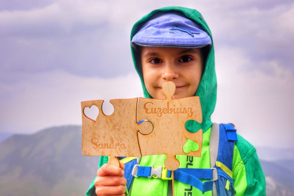 Zadowolone dziecko trzymające dwa duże puzzle z napisem Sandra oraz Euzebiusz - Trzydniowiański Wierch