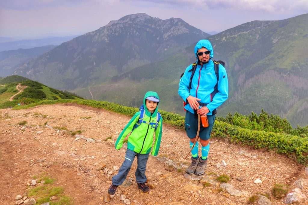 Zadowolone dziecko z tatą na ostatnim odcinku szlaku czerwonego na Trzydniowiański Wierch, w tle tatrzańskie szczyty