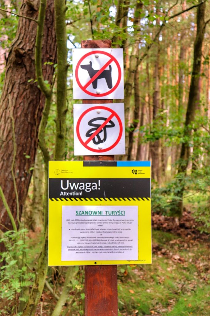 Tablica informacyjna Słowińskiego Parku Narodowego, znaki zakazu wprowadzania psów oraz zbierania grzybów