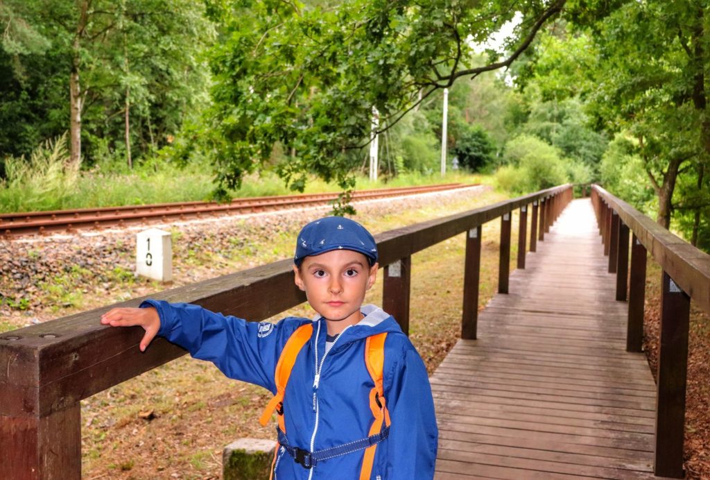 Dziecko, drewniane przejście idące wzdłuż torów koło stacji Ustka Uroczysko
