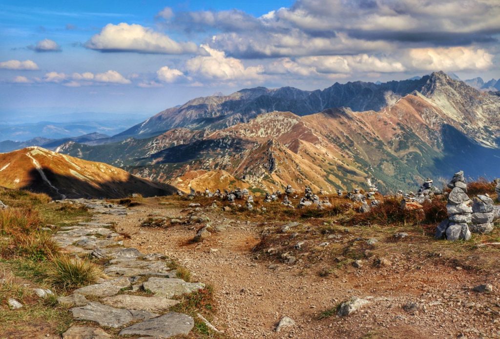 Jesienne krajobrazy widziane ze szczytu Krzesanica, niebo pokryte białymi chmurami, kamienne kopczyki